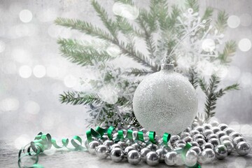 Fototapeta na wymiar Light Christmas background. Branch, spruce, ball, beads and streamers on bright blurred background is bokeh.