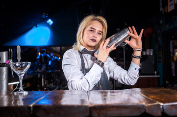 Girl barman formulates a cocktail in the public house