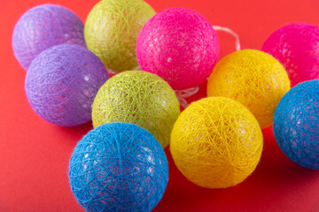 Heap of magenta, green, blue, yellow rnitted balls on red background.