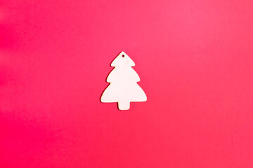 Wooden Christmas tree toy on a red background. Natural Christmas decor concept. Copy space. Top view. Horizontal orientation. Minimalism.