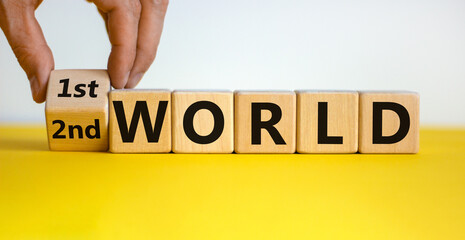 Male hand flips a wooden cube and changes the inscription '2nd world' to '1st world'. Beautiful yellow table, white background, copy space. Business concept.