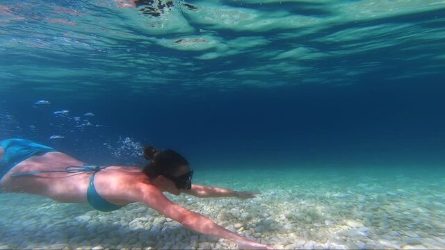 Young woman snorkeling in crystal clear water of Antisamos beach in Kefalonia