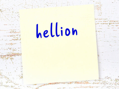 Yellow sticky note on wooden wall with handwritten word hellion