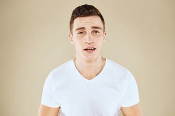Emotional man and white t-shirt gesturing with hands beige cropped background