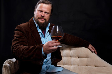 Stylish bearded man dressed in brown jacket with glass of whisky