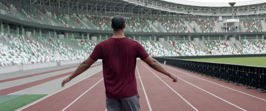 Portrait of African American Black male warming up before running on an empty stadium track early in the morning. Shot with anamorphic lens