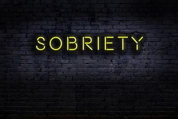 Night view of neon sign on brick wall with inscription sobriety