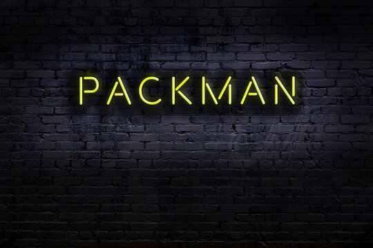 Neon sign. Word packman against brick wall. Night view