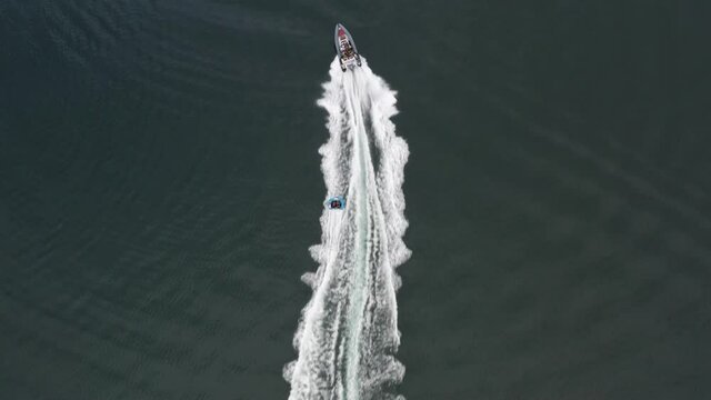Aerial top down view of a rib ride with doughnut attached, with crew having fun 4K 