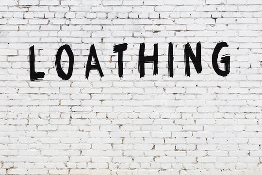 White wall with black paint inscription loathing on it