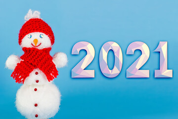 Fototapeta na wymiar Cute white snowman in a red hat on a light blue background, holographic numbers 2021 