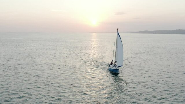 Sunrise sailing off the coast of the Isle of Wight. Aerial orbit of isolated sail boat 4k