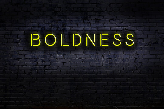 Night view of neon sign on brick wall with inscription boldness