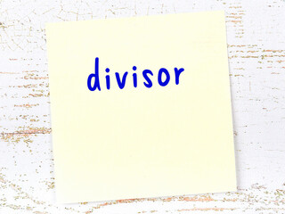 Yellow sticky note on wooden wall with handwritten word divisor - obrazy, fototapety, plakaty