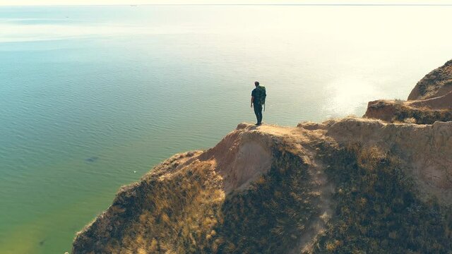 The traveler is standing on the mountain cliff on the seascape background