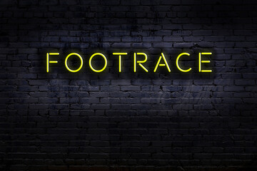 Neon sign. Word footrace against brick wall. Night view