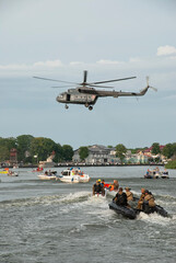 Fototapeta na wymiar Military helicopter Mi-8 poses above the boats. The photo was taken during a public show, where everyone could photograph without restrictions. Commando Fest in Dziwnów - August 22, 2020.