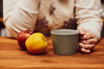 Young woman holding hot cocoa or coffee cup. Autumn or winter moody weekend, New Year, and Christmas background. Lazy day, light breakfast, quarantine, stay home, cozy scene, hygge concept.