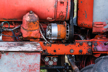 Closeup of four cylinder diesel tractor engine with visible belt rusty tracks hydraulic parts and...