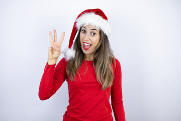Young beautiful woman wearing a Santa hat over white background showing and pointing up with...