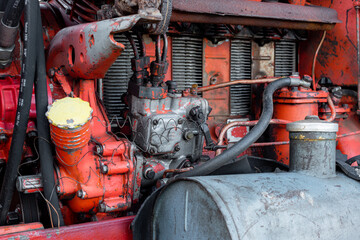 Old silver painted diesel tank on red vintage russian tractor engine visible wiring rust and oil drops on sunny autumn day in rural Bulgaria