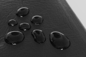 Liquid droplets run down the leather surface. Rain or expression of emotion. Black and white shot. Close-up. Shallow depth of field.