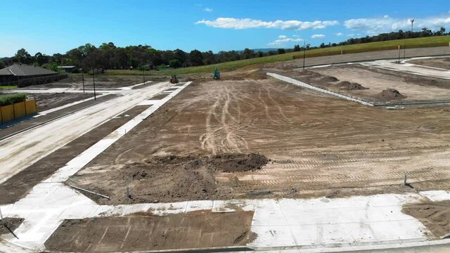 Aerial footage looking ahead, slowly flying over an undeveloped lot of land in a new housing estate in suburban Australia