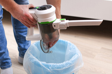 A man uses a bagless vertical cordless vacuum cleaner to clean the floor.