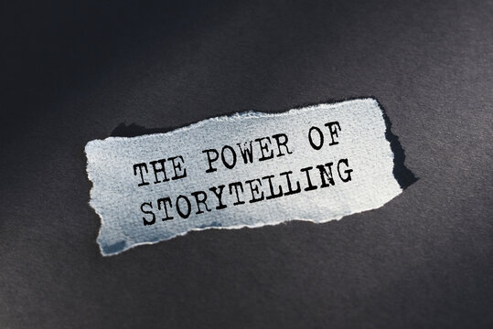 The power of storytelling is text on torn paper on a dark table in sunlight.