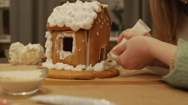 Close-up of handmade gingerbread house decorated with lots of cream on christmas table