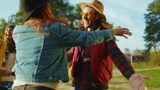 Stylish hipster friends met eath other in nature. Four young people hug smiling with dog. Vacation tourism adventure outdoors. Close up. Slow motion