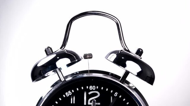 Close-up of vintage alarm clock ringing isolated on white background. Traditional alarm clock in motion, bell alarming, wake up morning concept, deadline, attention, time