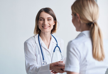 Fototapeta premium Woman doctor with glasses in hands on a light background patient communication
