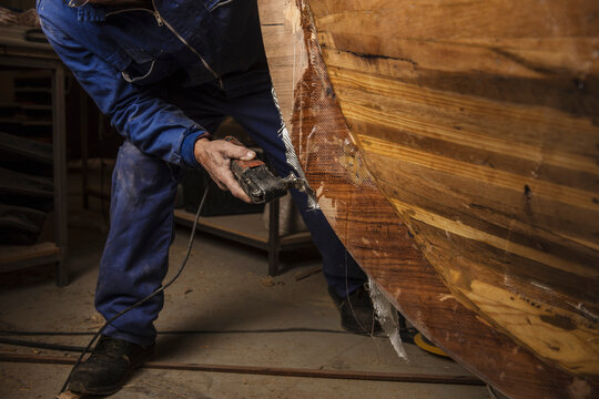 old man polishing the keel of a traditional boat he is building