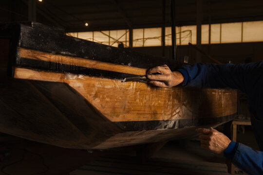 retired man retouching with a chisel the traditional boat he is building