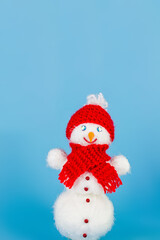 Christmas blue background of a snowman in a red hat smiling in a scarf