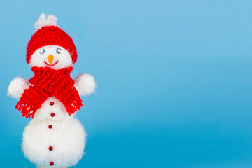Christmas blue background of a snowman in a red hat smiling in a scarf