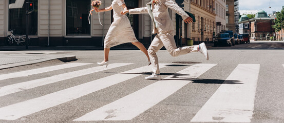 Bridal couple running across the street in Copenhagen. Wedding agency concept. - 392141893