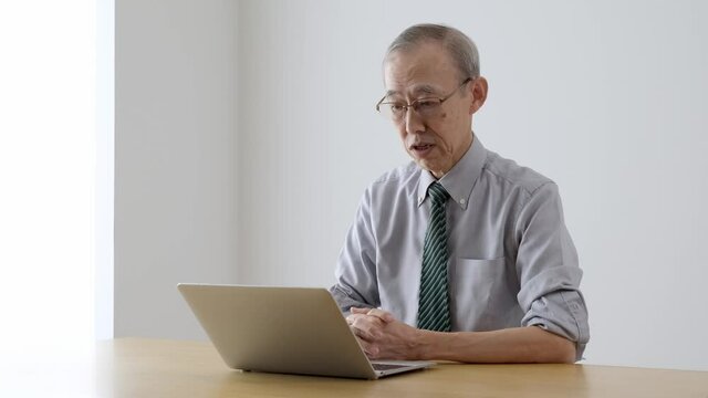 パソコンでビデオチャットをするシニア男性
