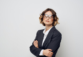 A business woman in glasses and in a suit on a light background crossed her arms over her chest