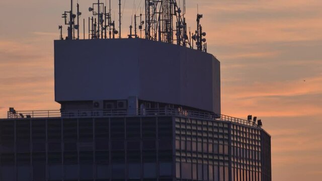 Multiple Broadcasting Antennas on top of High Rise Building at Sunrise