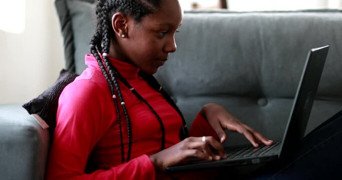 African adolescent girl doing homework in front of laptop screen