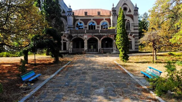 The Pommer Mansion, old abandoned building with green trees and benches on the yard. Aerial drone view. Țaul, Moldova