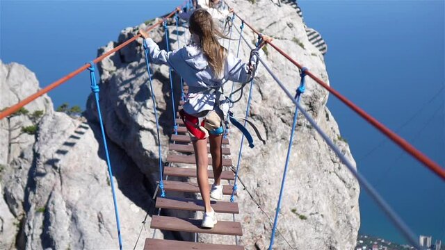 Girls crossing the chasm on the rope bridge. Black sea background, Crimea