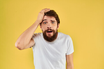 A man in a white t-shirt gestures with his hands lifestyle cropped view yellow background more fun
