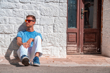 Young man sitting by the trulli houses in Alberobello, province Bari, region Puglia, Italy....