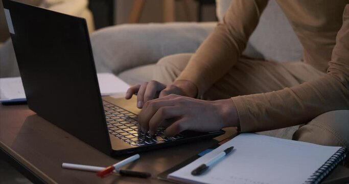 Man working on laptop and writing notes at home office