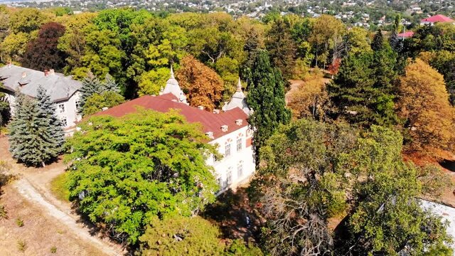 The Pommer Mansion, old abandoned building with green trees and benches on the yard. Aerial drone view. Țaul, Moldova