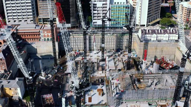 Descending aerial view of Queen's Wharf construction site with high cranes in Brisbane CBD, QLD Australia