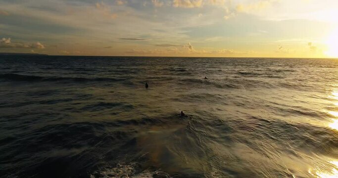 Drone video of surfers catching the waves at sunset.